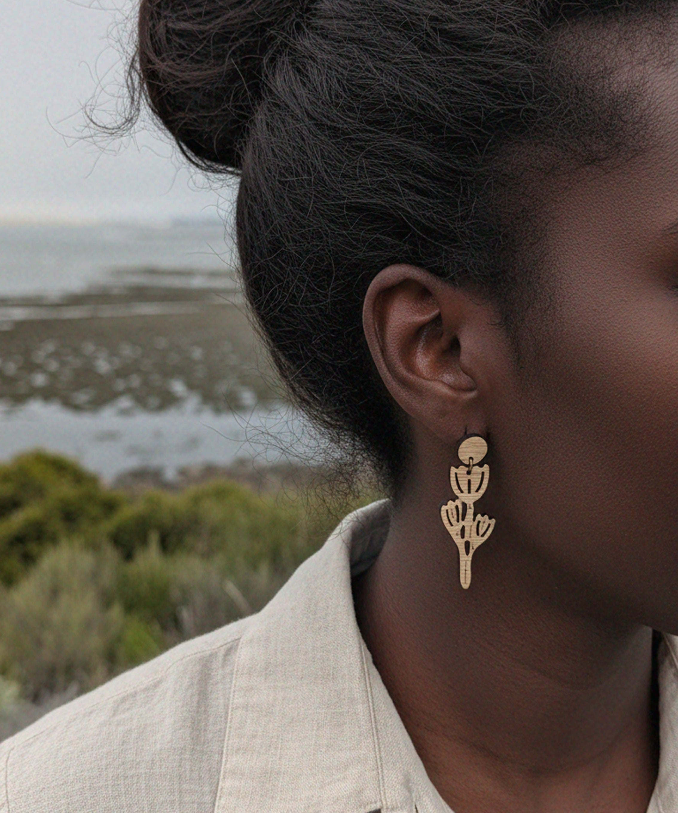 Person wearing california poppy bamboo earrings with a natural setting in the background