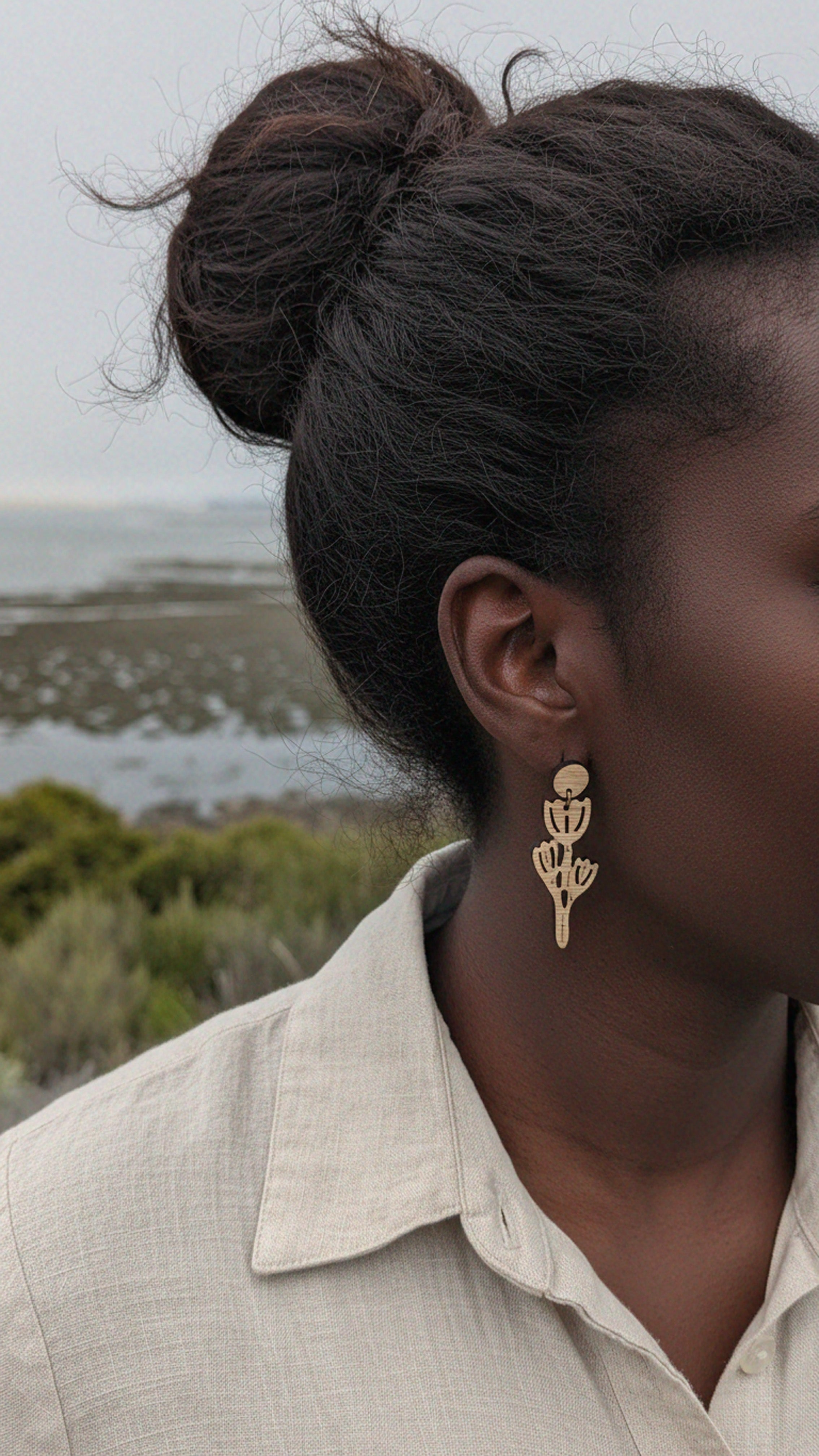 Person wearing california poppy bamboo earrings with a natural setting in the background
