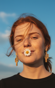 Large Cactus wood earrings worn by Woman with a flower in her mouth against a blue sky