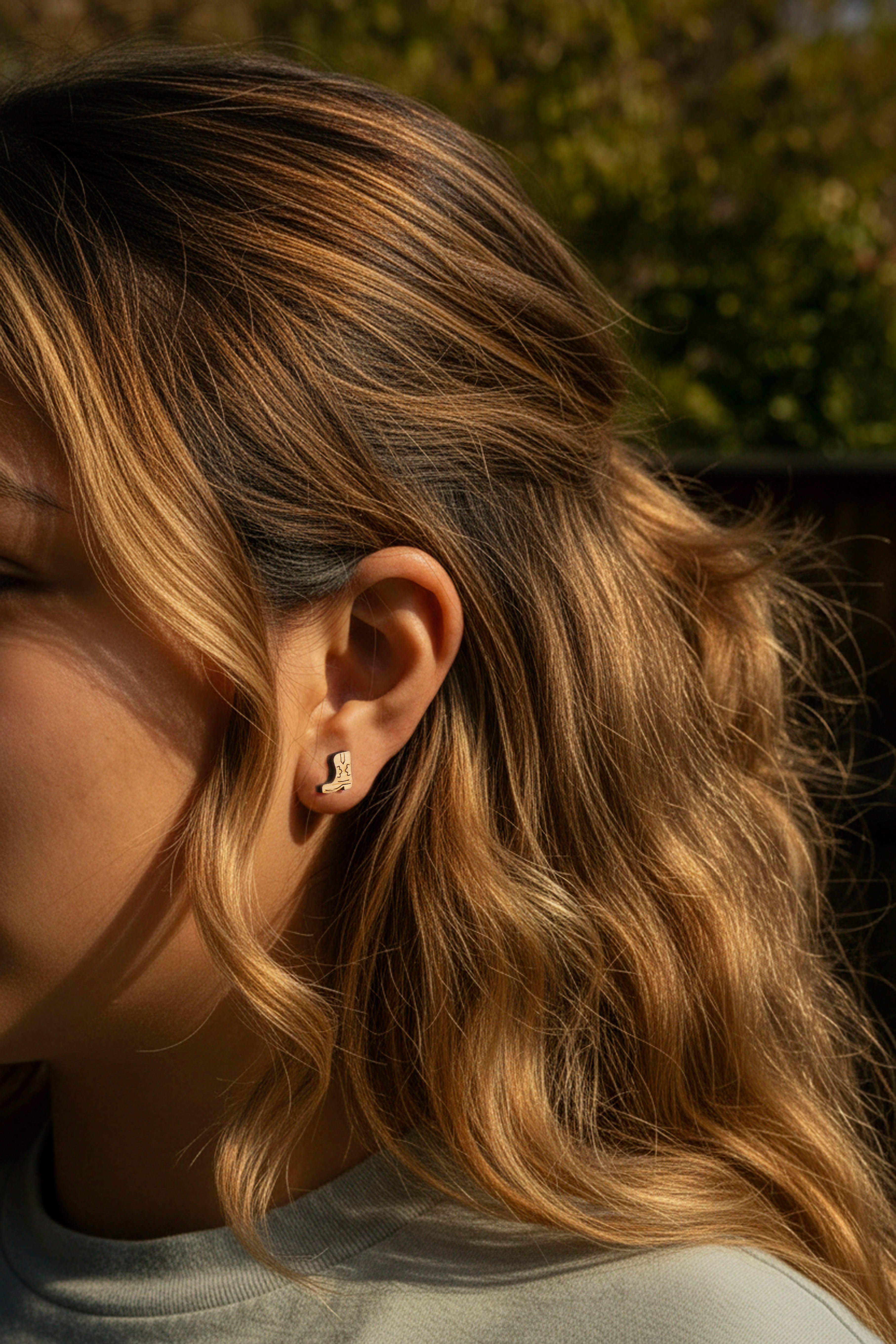 women wearing cute and tiny cowboy boot earrings on a natural background