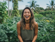 Woman laughing wearing arch bamboo drop earring in a lush green garden with palm trees in the background
