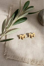 bighorn sheep earrings on a textured beige surface with olive branches.