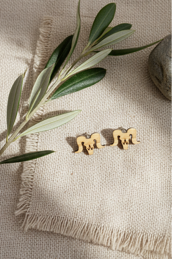 bighorn sheep earrings on a textured beige surface with olive branches.