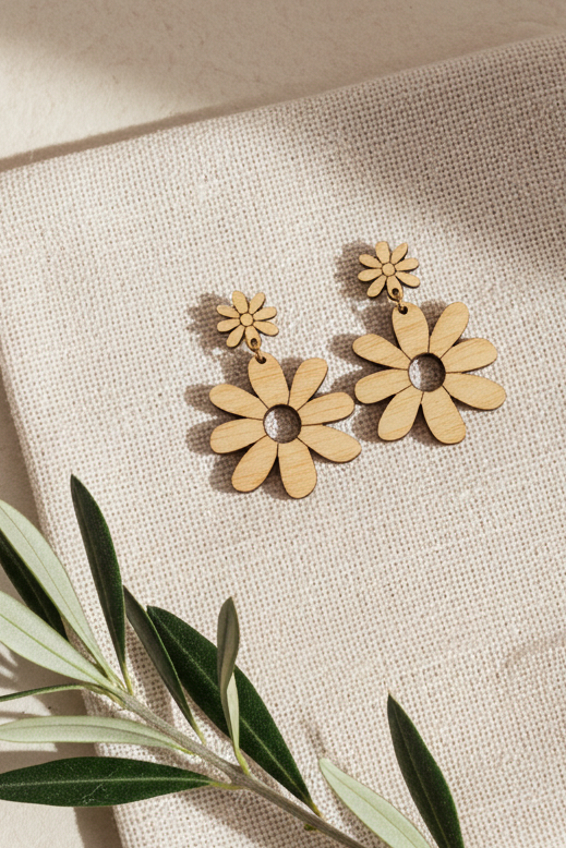 Wooden daisy-shaped earrings on a beige fabric background with a branch.