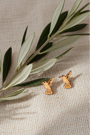 wood hummingbird earrings on a beige fabric background with an olive branch.
