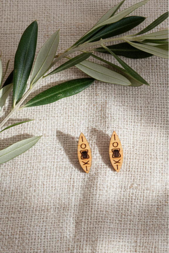 Wooden kayak-shaped stud earrings on a textured beige surface with olive leaves.