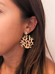 Coral-shaped wood dangle earrings worn by a person with a neutral background