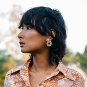 Woman with short dark hair wearing minimalist drop wooden earrings and a floral shirt outdoors. Perfect gift for your environmentally conscious friends.