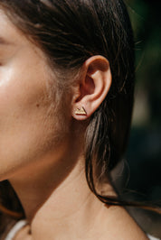 Close-up of a person wearing a bamboo mountain stud earring with a blurred background