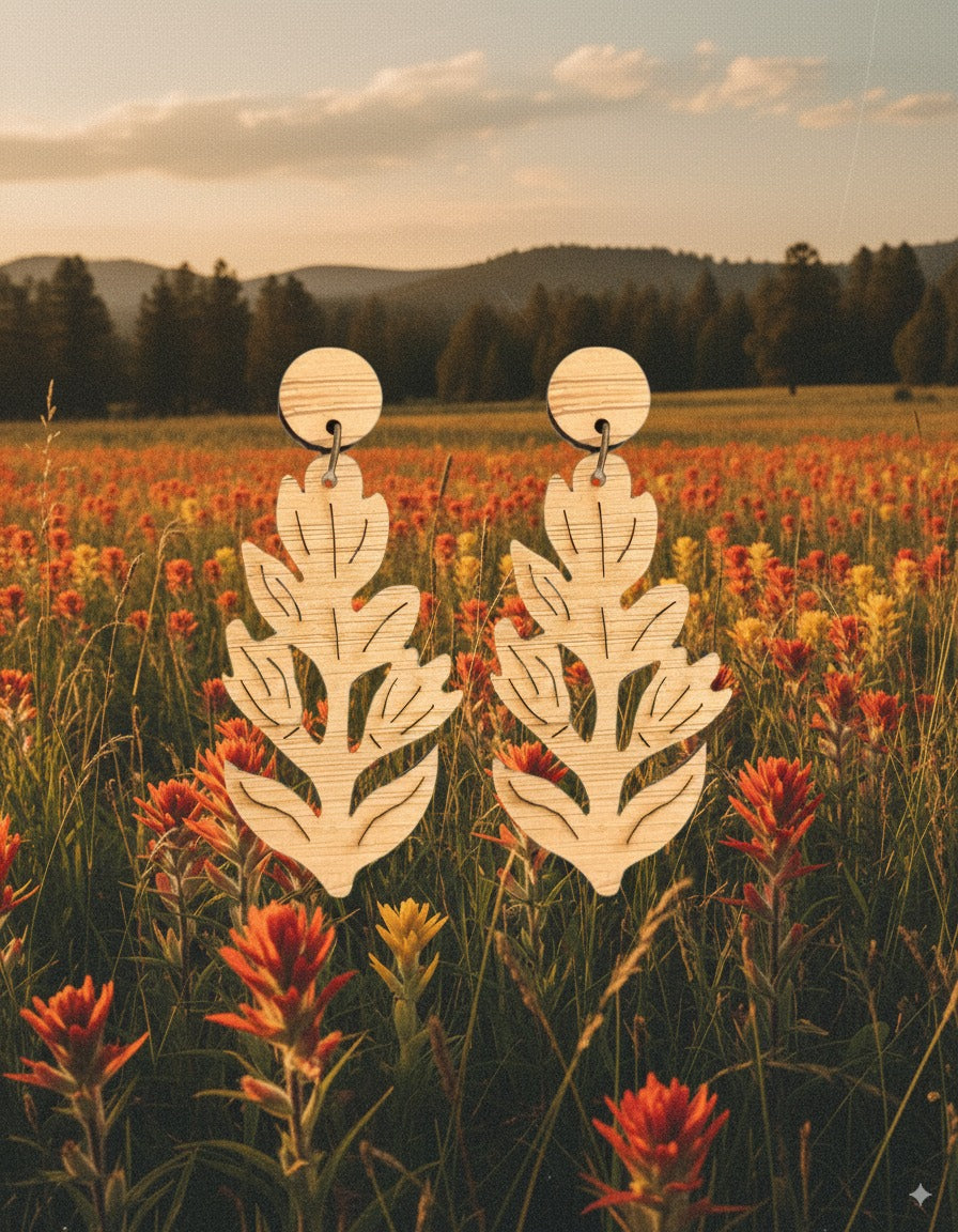 Handmade laser cut bamboo paintbrush flower dangle earrings with a field of flowers and mountains in the background