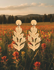 Handmade laser cut bamboo paintbrush flower dangle earrings with a field of flowers and mountains in the background
