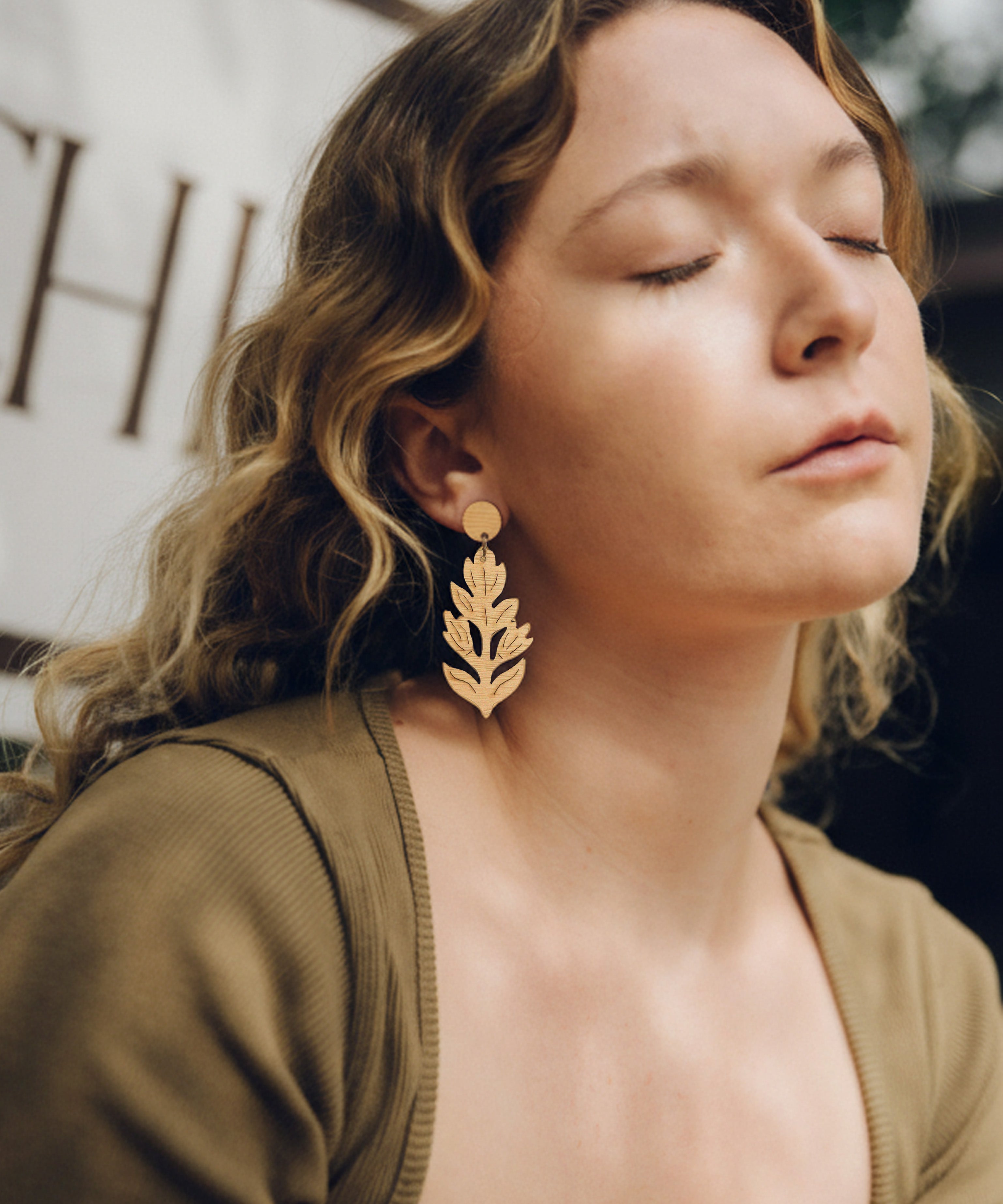 Woman wearing paintbrush flower dangle earrings with a blurred background