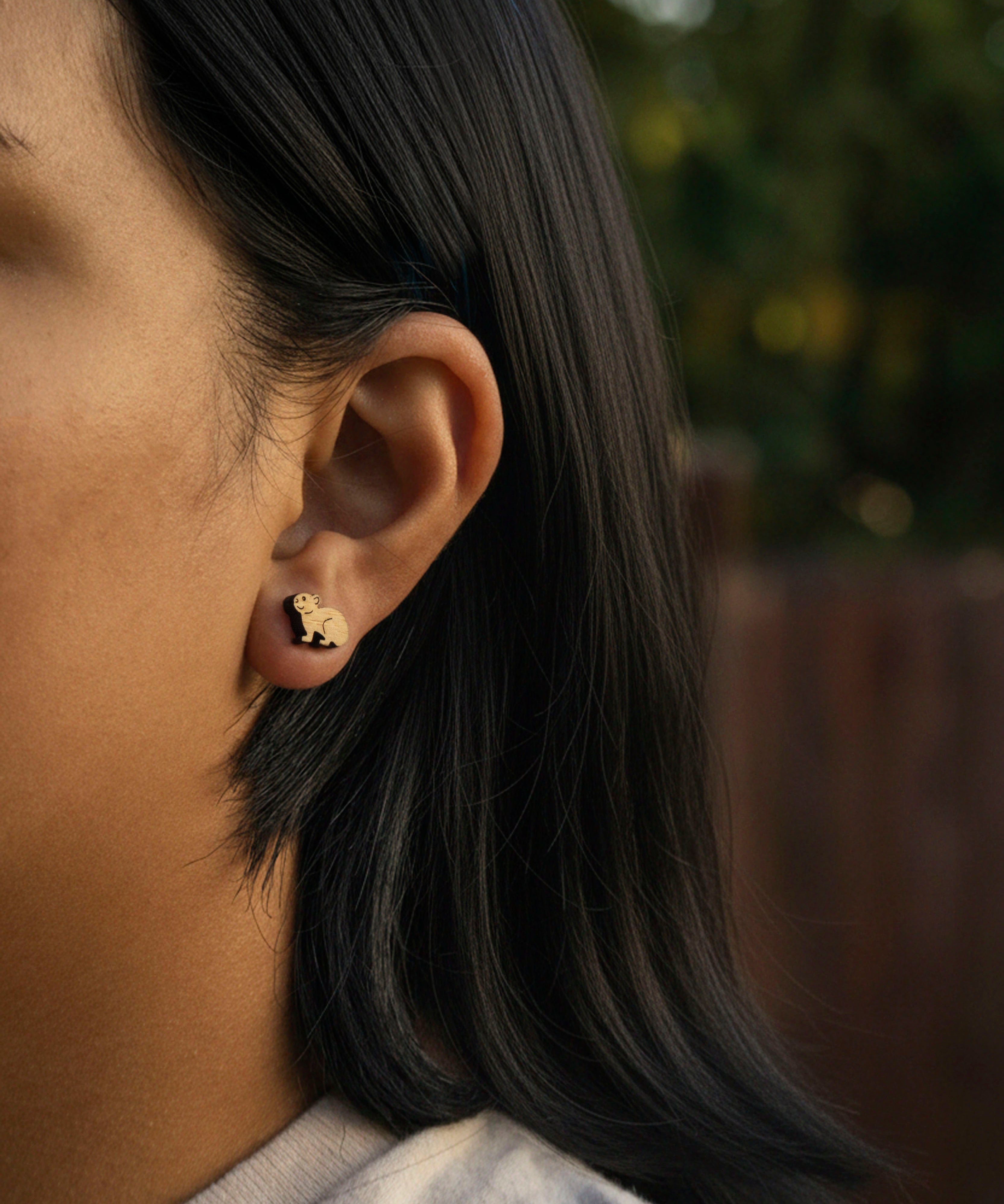 Close-up of a person wearing a cute pika stud hypoallergenic earring with a blurred background