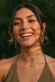 Woman smiling with a snake dangle earrings natural background