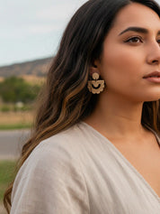 Woman wearing large sun inspired drop wood earrings earrings outdoors with a blurred natural background