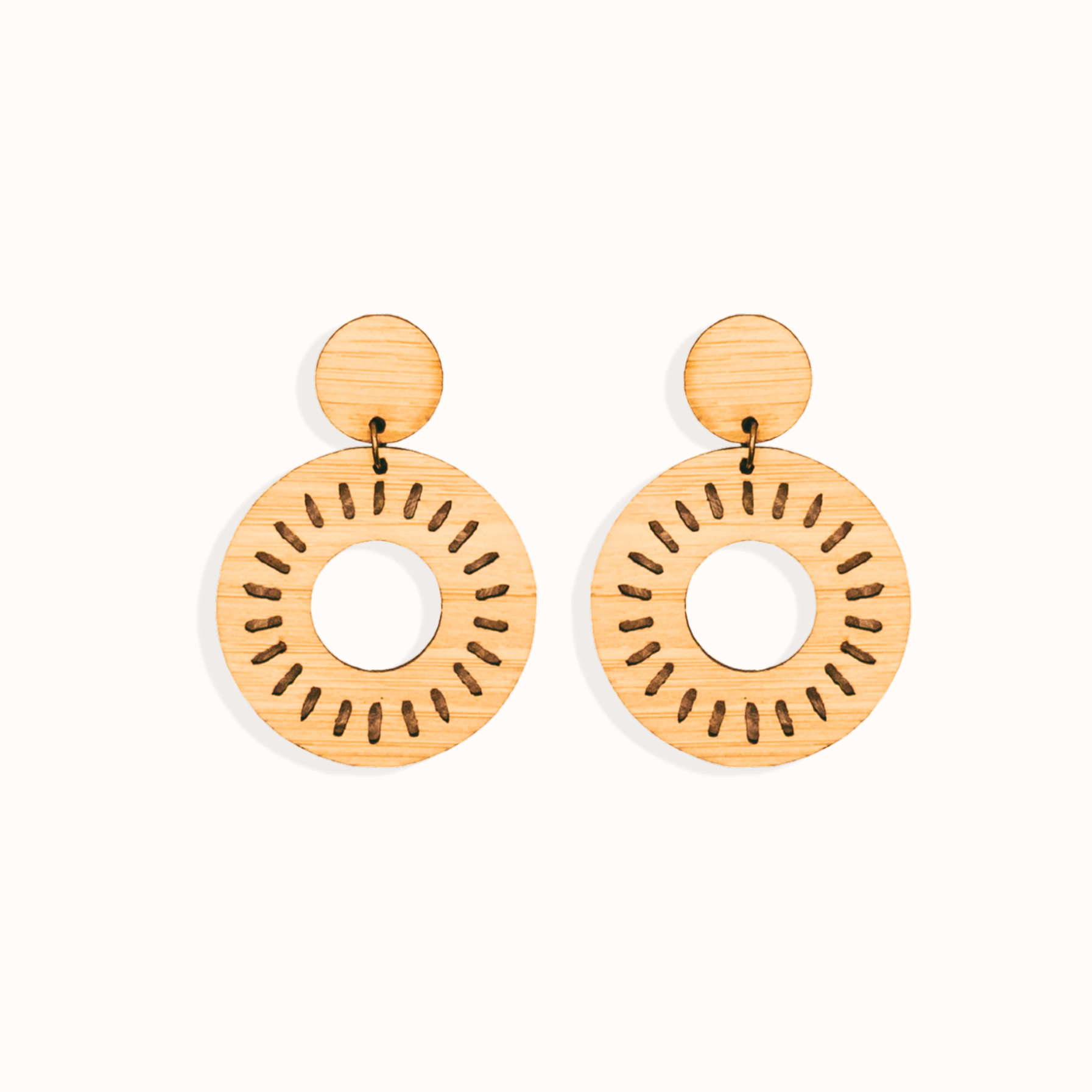 Pair of laser cut bamboo earrings with circular sun design on a white background. Perfect gift for your environmentally conscious friends.
