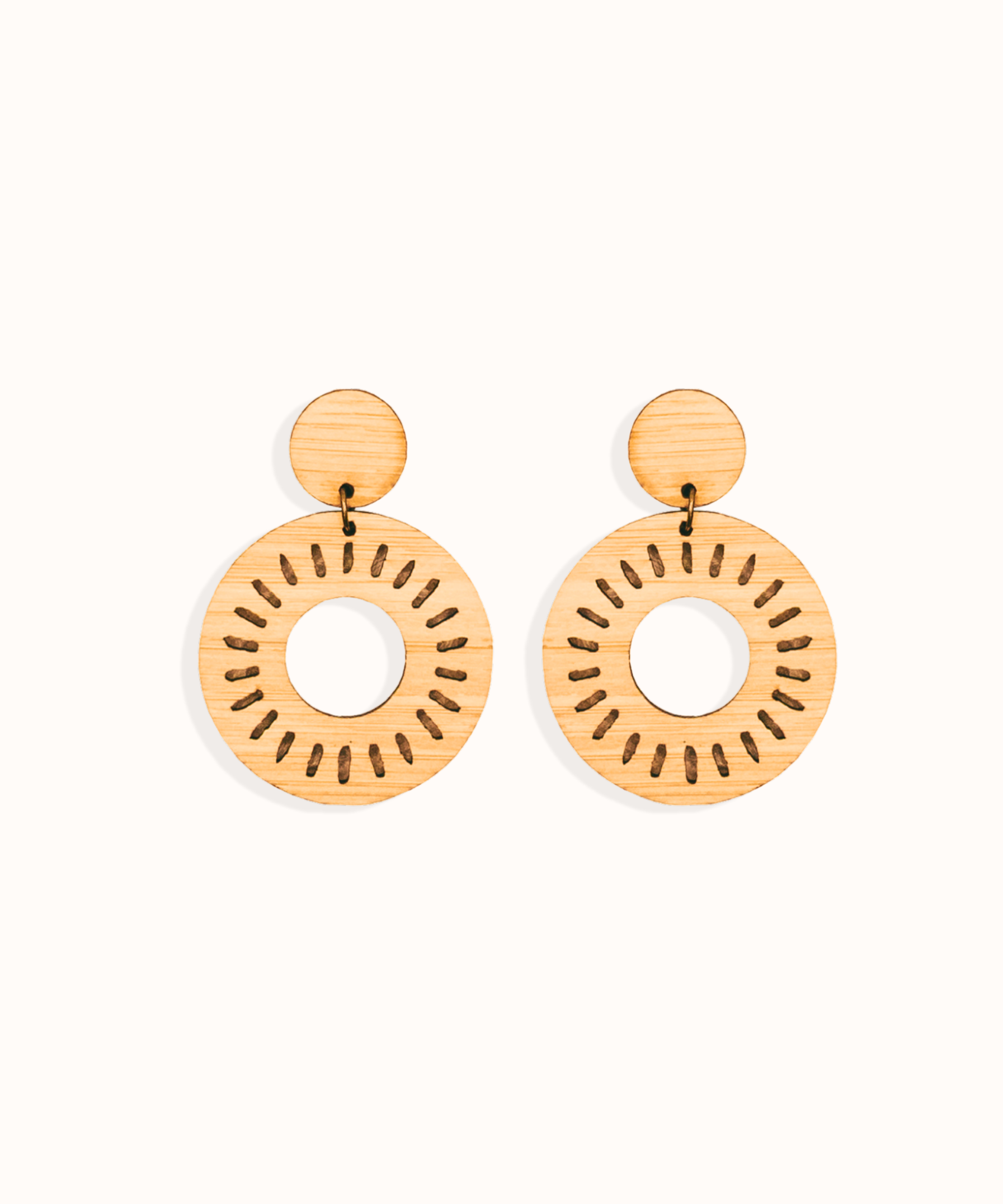 Pair of laser cut bamboo earrings with circular sun design on a white background. Perfect gift for your environmentally conscious friends.