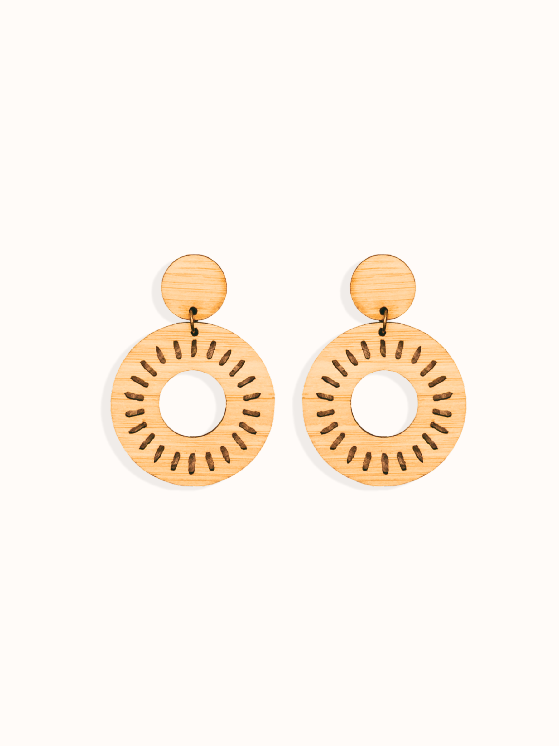 Pair of laser cut bamboo earrings with circular sun design on a white background. Perfect gift for your environmentally conscious friends.