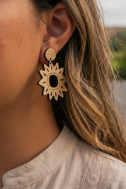 Close-up of a person wearing a sun-shaped wooden laser cut earring.